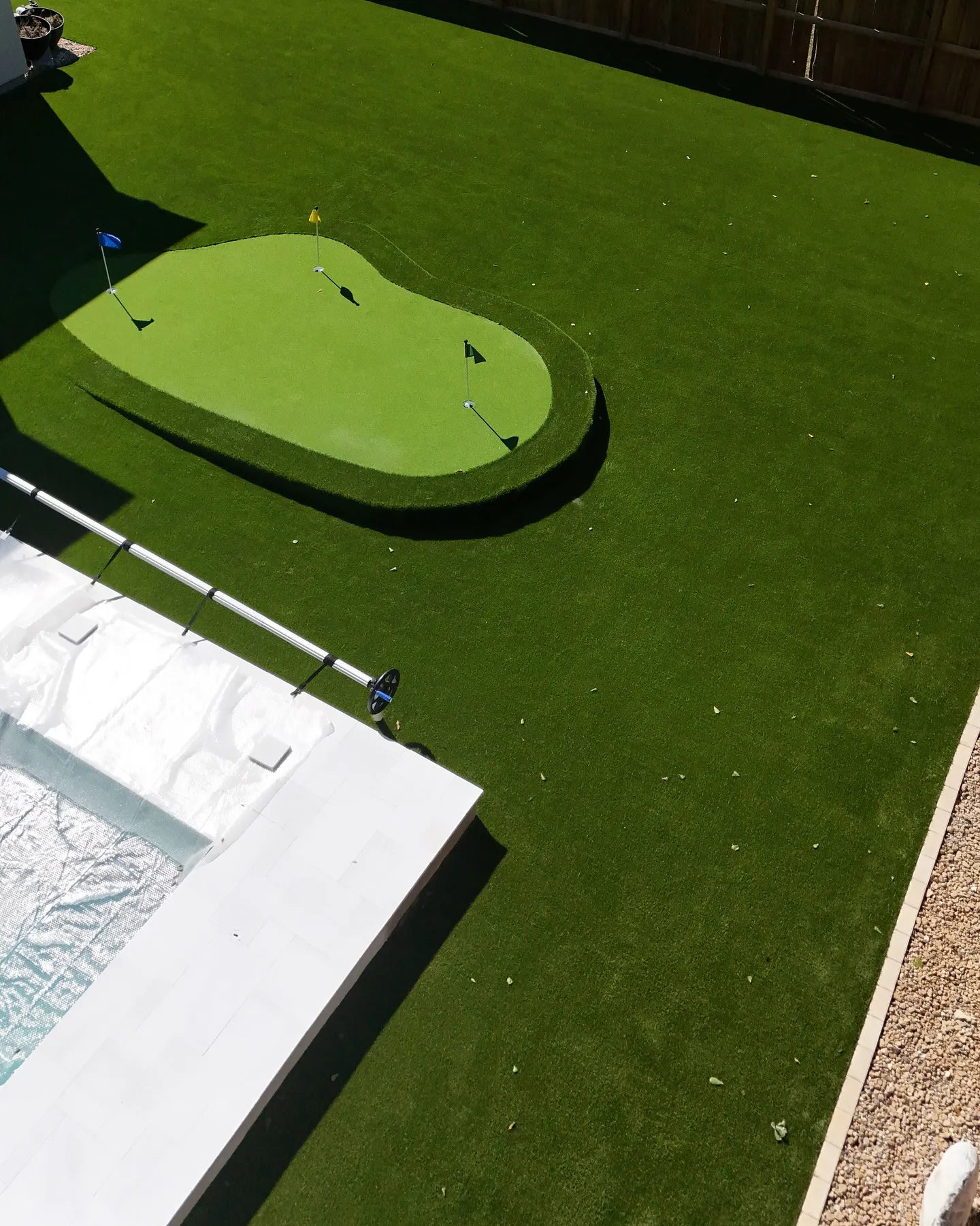 Custom kidney-shaped putting green with surrounding turf lawn