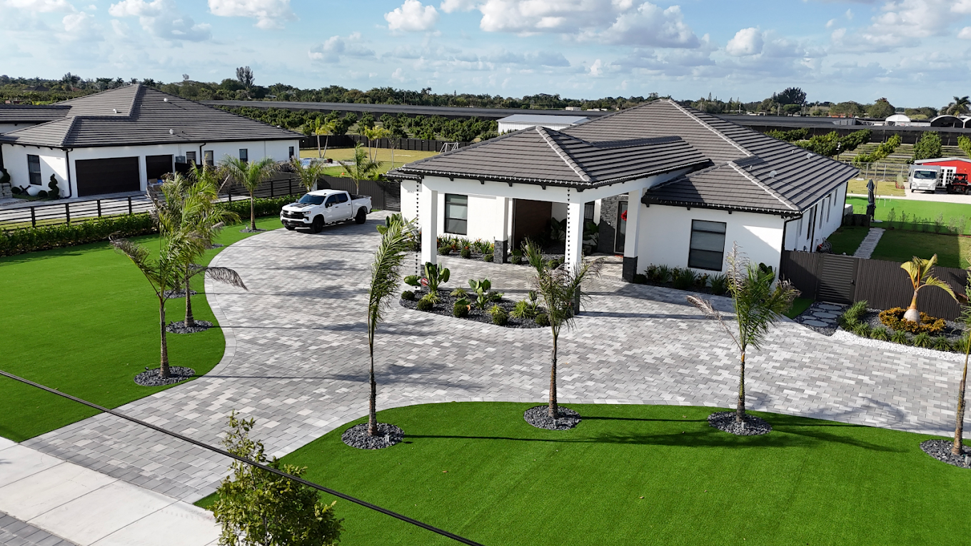 Luxury front yard artificial turf install with palm trees and circular driveway