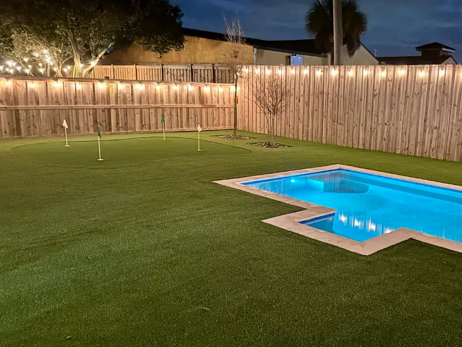 Nighttime backyard putting green next to pool