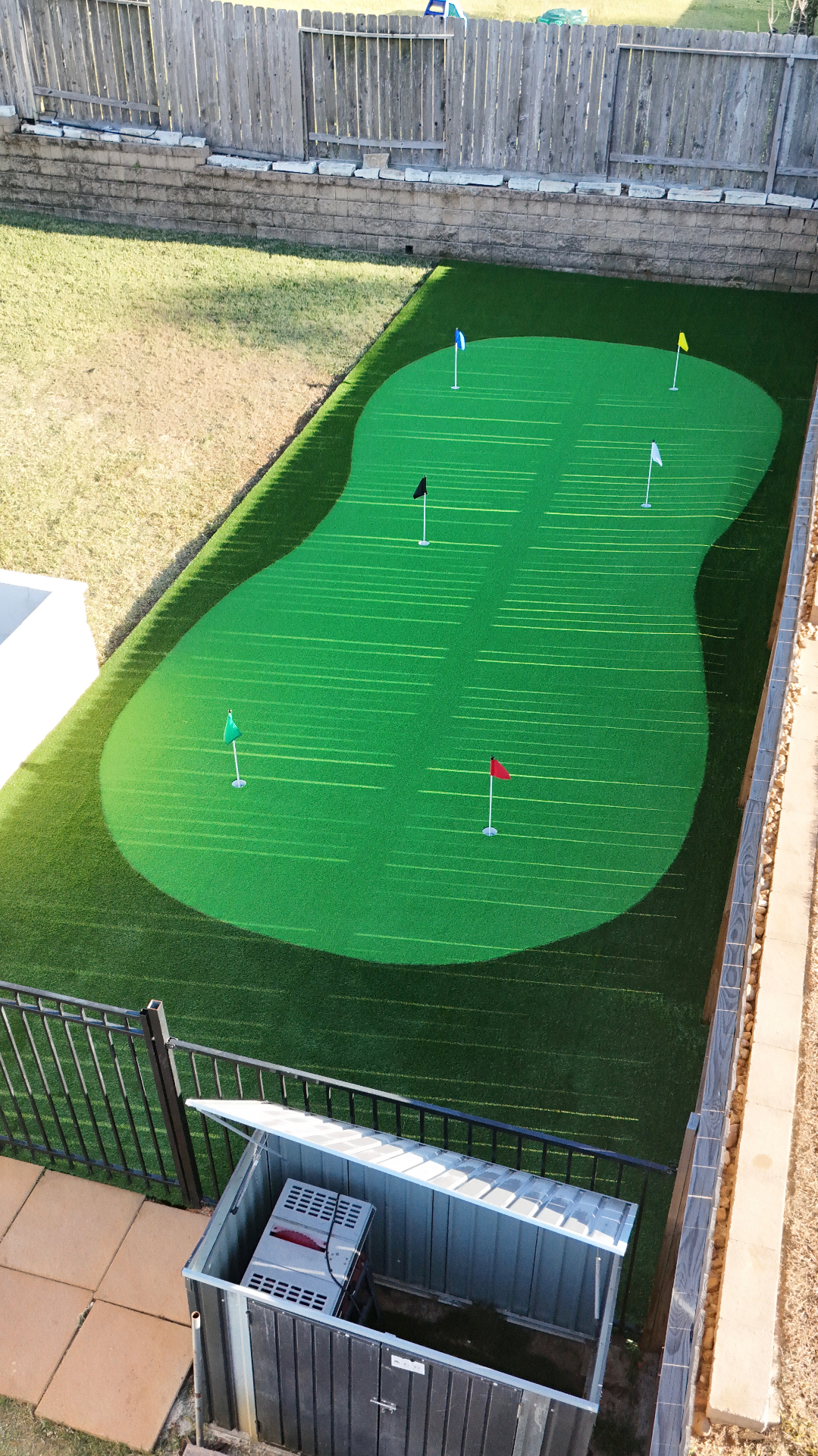 Large multi-flag backyard putting green with dark turf fringe collar
