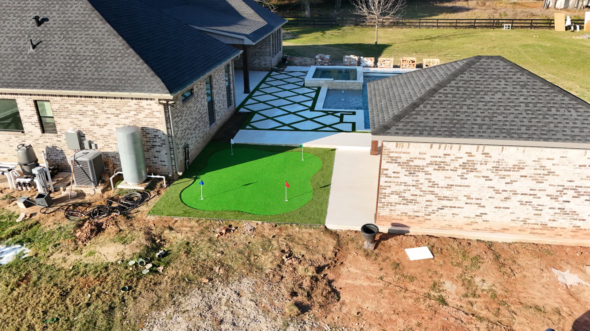 Custom putting green with three cups installed beside a Houston pool