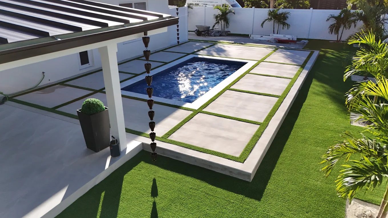 Modern poolside turf with concrete pavers and tropical landscaping